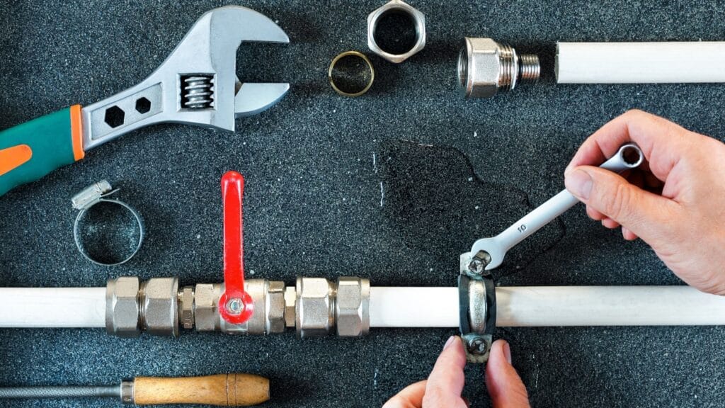 Plumber repairing a pipe valve with an adjustable wrench in West Palm Beach