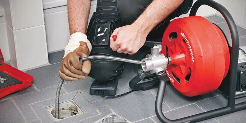 Plumber using a drain-cleaning machine in West Palm Beach