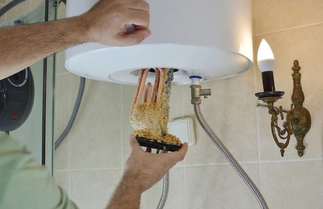 Technician removing mineral buildup from a water heater in West Palm Beach