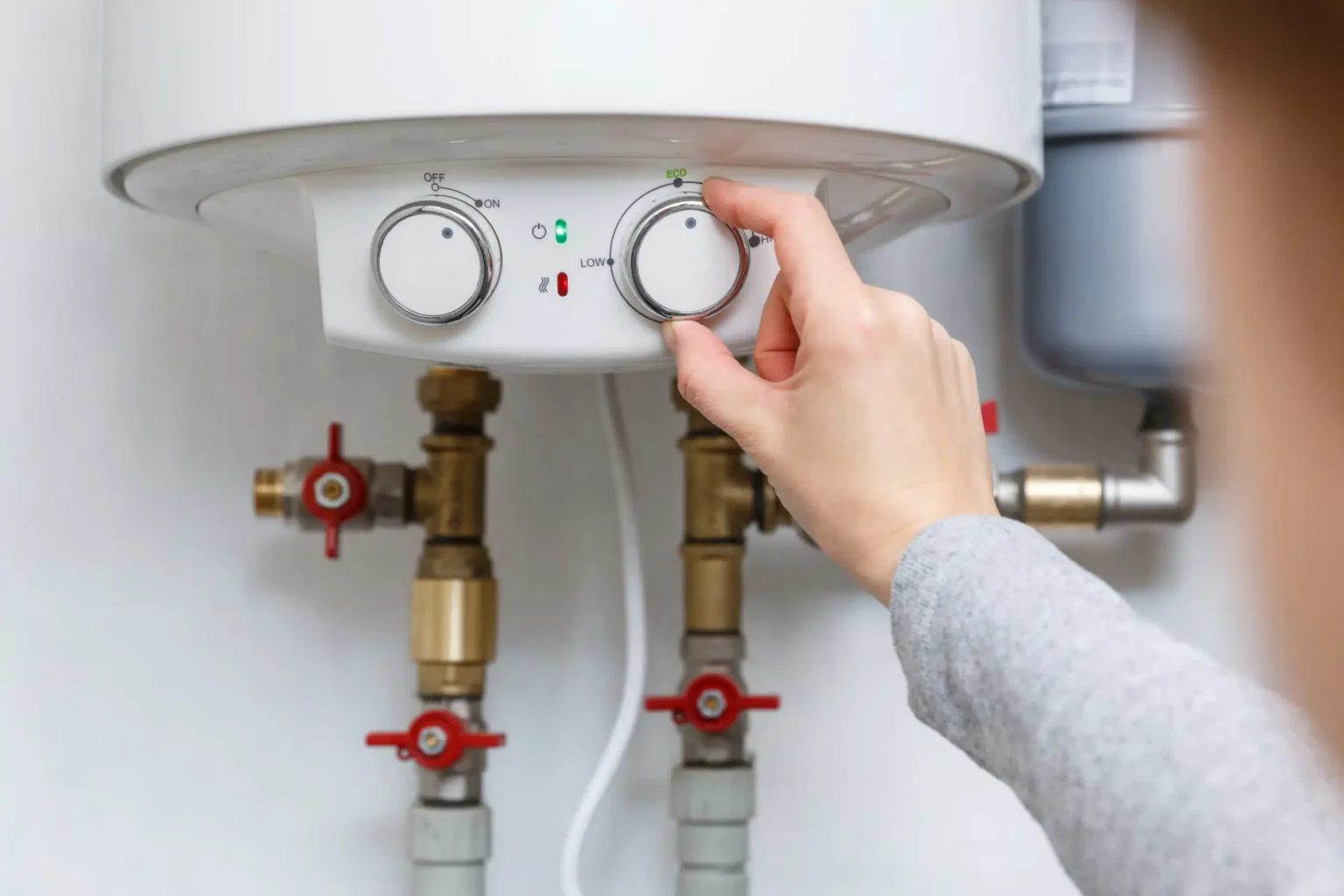 Homeowner adjusting the temperature controls on a water heater in West Palm Beach